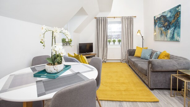 A modern living room with a sofa, a dining table, and a TV. - 1 Bedroom City Centre Holiday home (York)