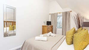 A bedroom with a bed, a dresser, a mirror, and a window with curtains. - 1 Bedroom City Centre Holiday home (York)