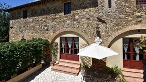 A stone building with arched doorways and a patio area with outdoor furniture. - Near Siena (6 km), in Chianti, swimming pool and terrace, Wi-fi, A / C (Villa parigini)