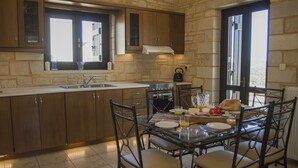 Une cuisine avec des murs en pierre, des meubles de rangement en bois, une table à manger avec des chaises et une fenêtre.