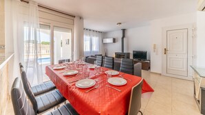 A dining area with a red tablecloth, black chairs, and a TV in the background. - Olivia: Villa with private pool in L'Escala (L'Escala)