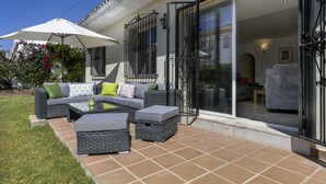 Un patio exterior con un conjunto de sofás, una mesa y una sombrilla grande.