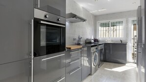 Cocina moderna con electrodomésticos de acero inoxidable, horno empotrado y lavadora.