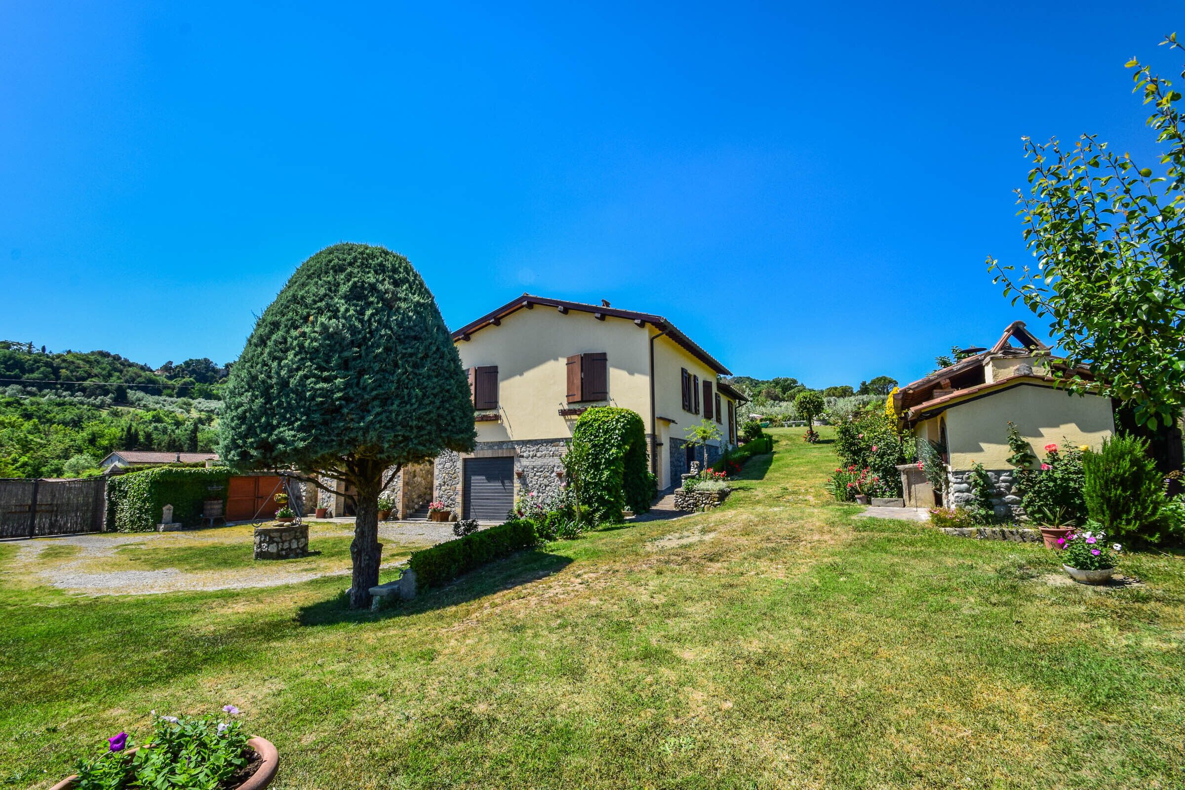 A two-story house with a stone facade, a well-maintained lawn, and a clear blue sky.