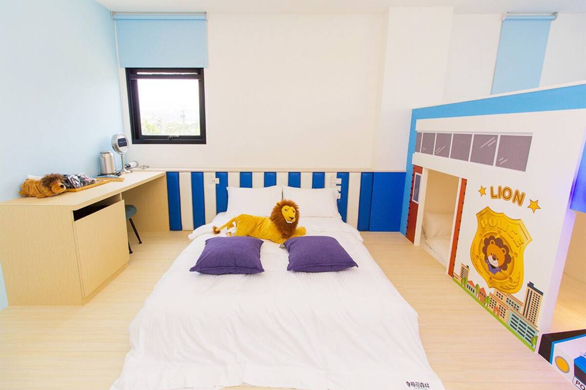 Ein Schlafzimmer mit Bett, Schreibtisch und einer Löwen-Plüschfigur.