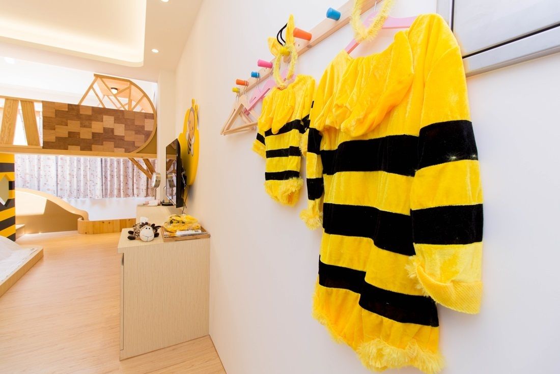 Una habitación con un escritorio de madera, un estante en la pared con varios objetos y un amplio ventanal con cortinas.