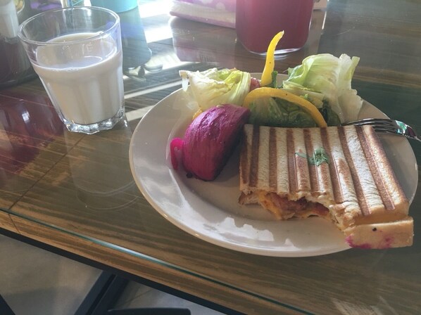 Un plato con un sándwich, ensalada y un vaso de leche sobre una mesa.