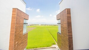 A modern building with a view of a green field through a glass window. - Plum Forest (Dongshan)