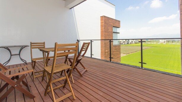 A balcony with wooden furniture and a view of a green field. - Plum Forest (Dongshan)