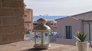A balcony with a lantern, a potted plant, and a view of the sea and buildings. - Two-room apartment 30 meters from the sea ideal for a family holiday (San Vincenzo)