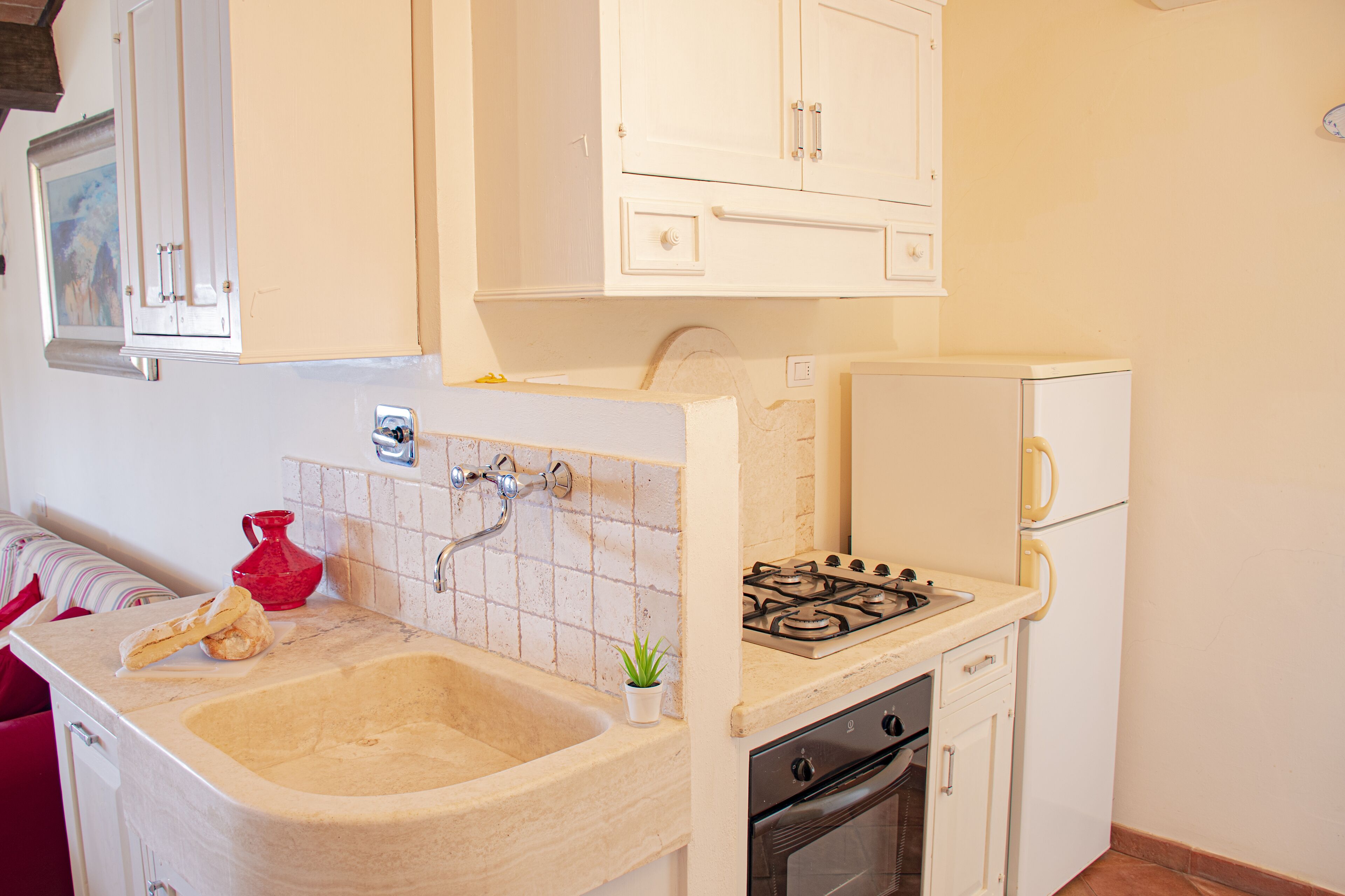 Una cucina compatta con lavello, fornello, forno e pensili.