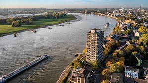 A river with a bridge, a large hotel, and surrounding urban landscape. - Hotel Rheingarten Duisburg (Duisburg)