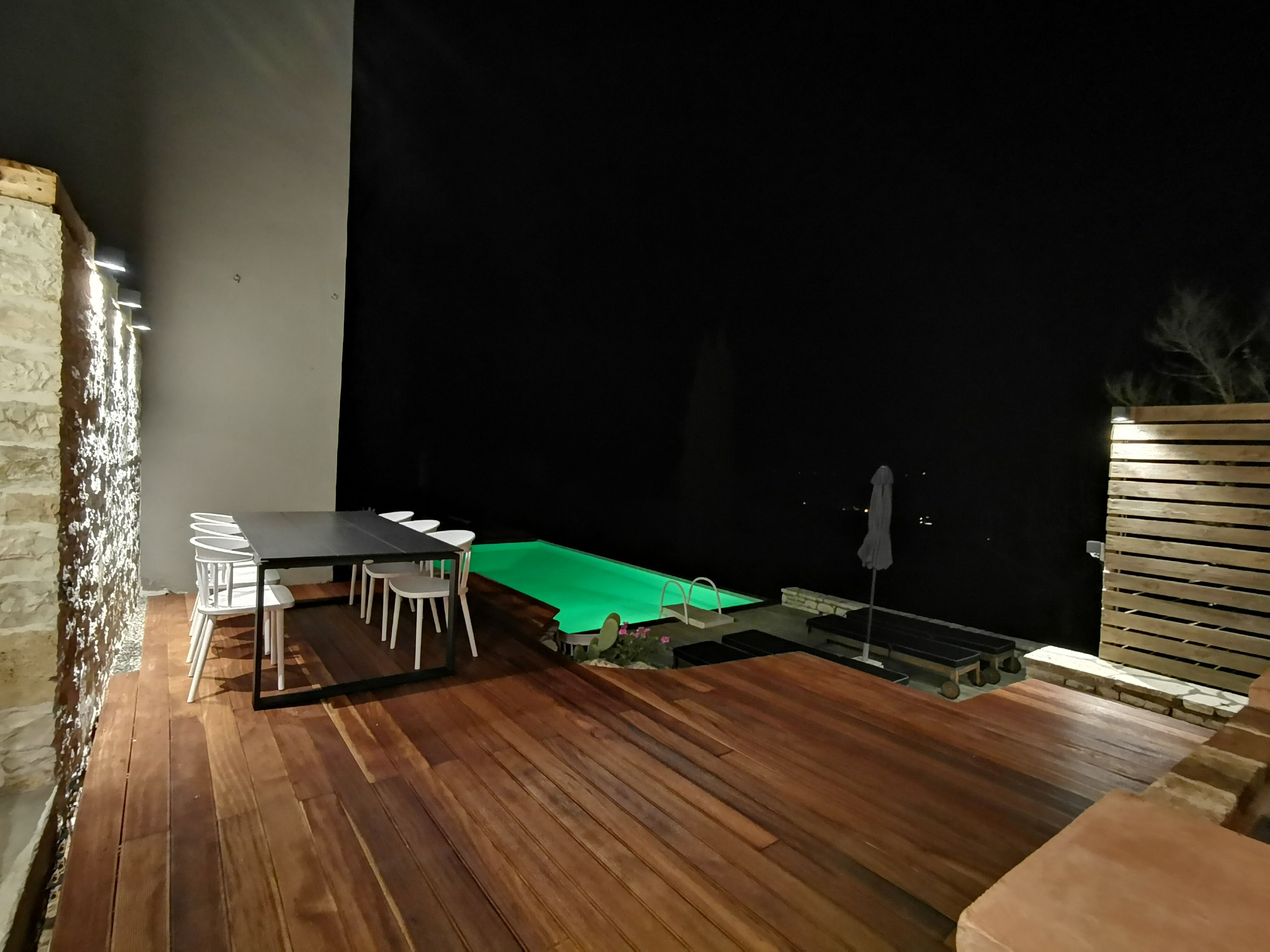 A wooden deck with a dining table and chairs, a small pool, and a wooden fence.