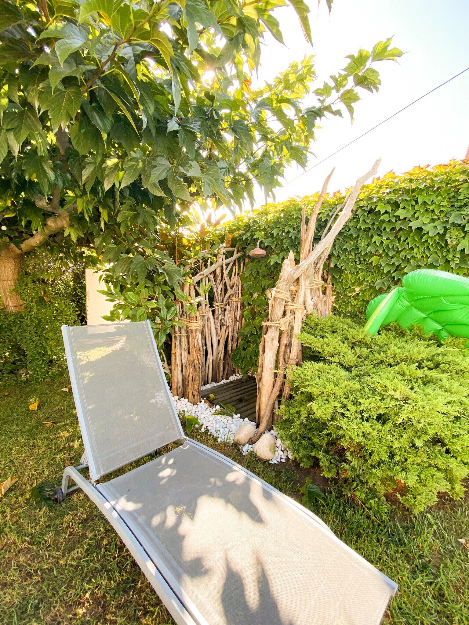 A garden with a metal chair, wooden fence, and green foliage.