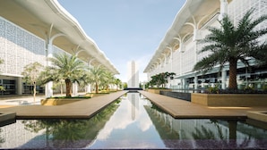 A modern building with a central reflective pool, symmetrical architecture, and palm trees. - Mövenpick Hotel & Convention Centre KLIA (Sepang)