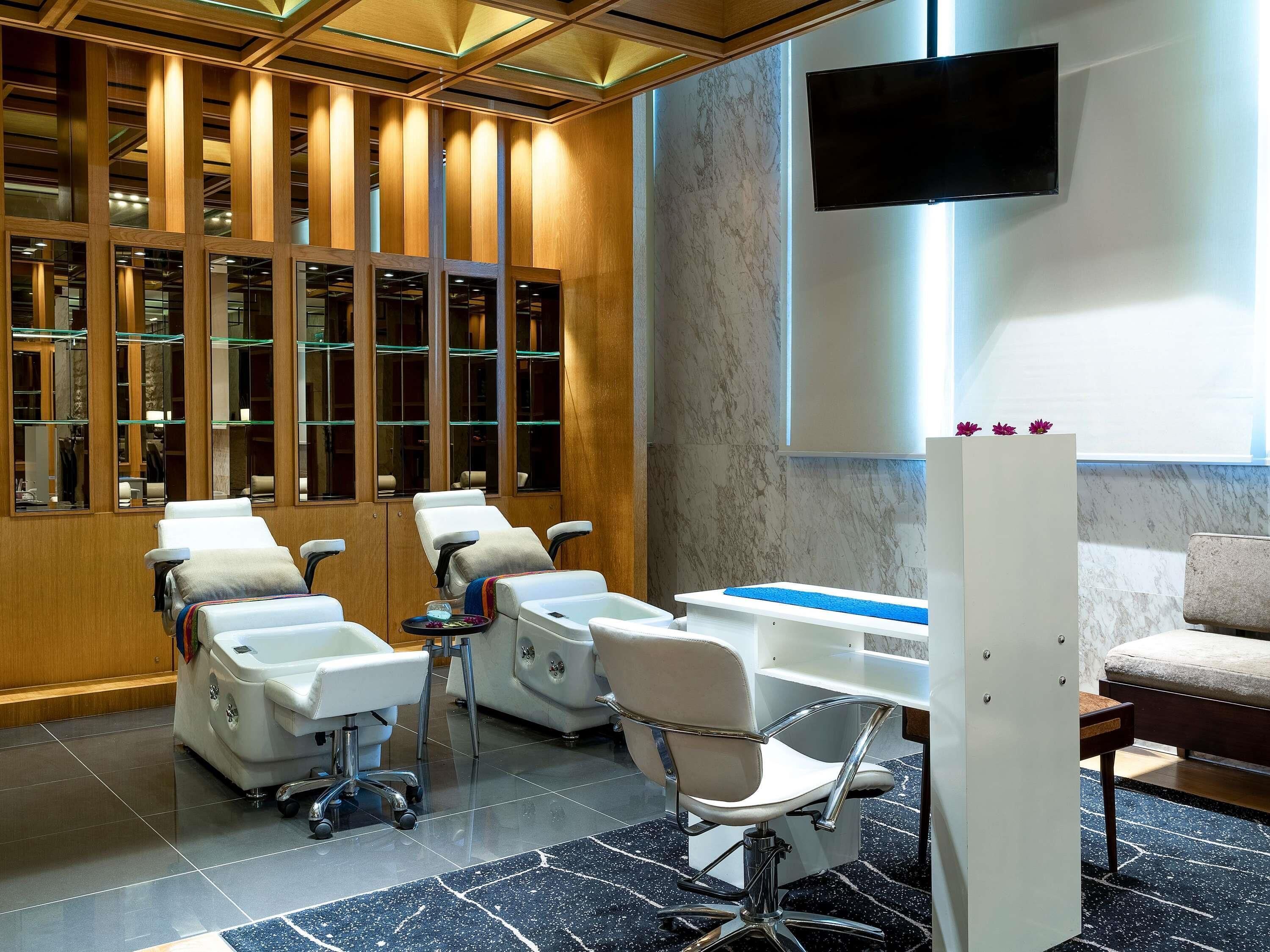 A modern hair salon with multiple hairdressing stations, a large mirror, and a flat-screen TV on the wall.