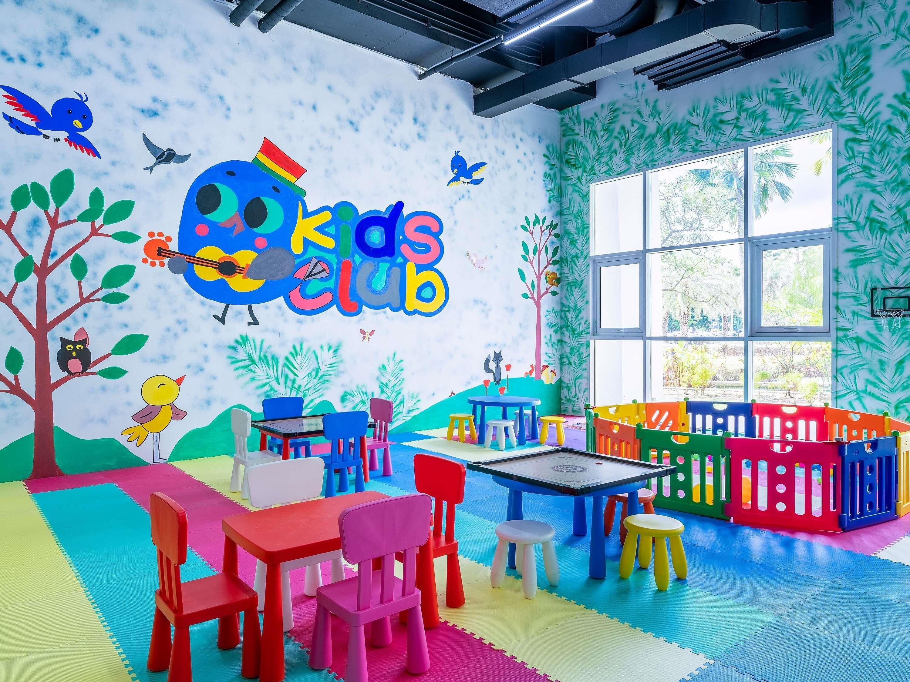 A children's play area with colorful furniture and a mural reading "Kids Club".