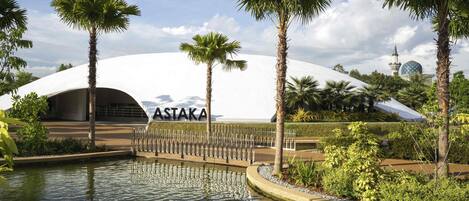 Un edificio moderno con una estructura en forma de cúpula y el nombre 'ASTAKA' a la vista.