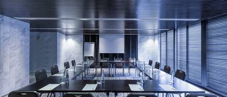 A conference room with a long table, chairs, and a projector screen.