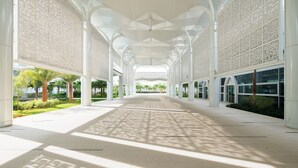 A covered walkway with patterned columns and a view of a landscaped area with palm trees. - Mövenpick Hotel & Convention Centre KLIA (Sepang)