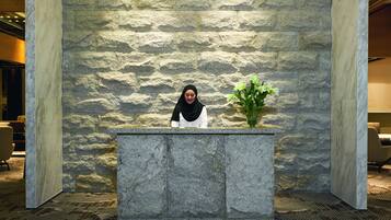 Un área de recepción con un fondo de pared de piedra, un mostrador de mármol y una planta en maceta.