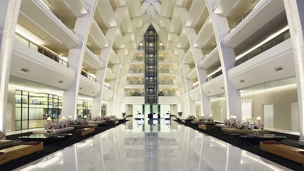 A modern hotel lobby with a central atrium, multiple floors, and a reflective floor. - Mövenpick Hotel & Convention Centre KLIA (Sepang)