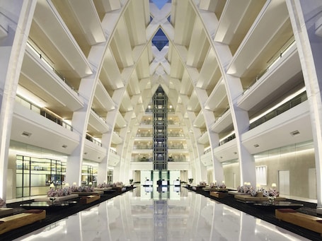 A modern hotel lobby with a central atrium, multiple floors, and a reflective floor.. Mövenpick Hotel & Convention Centre KLIA