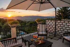 Una terrazza con vista sul tramonto, una piscina e mobili da esterno.