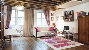 Een woonkamer met houten vloer, een witte bank, een salontafel en een boekenkast.