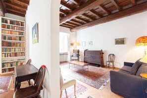 A cozy living room with a wooden ceiling, a bookshelf, a piano, and a sofa. - CHARMING APARTMENT CAMPO de'FIORI (Roma)