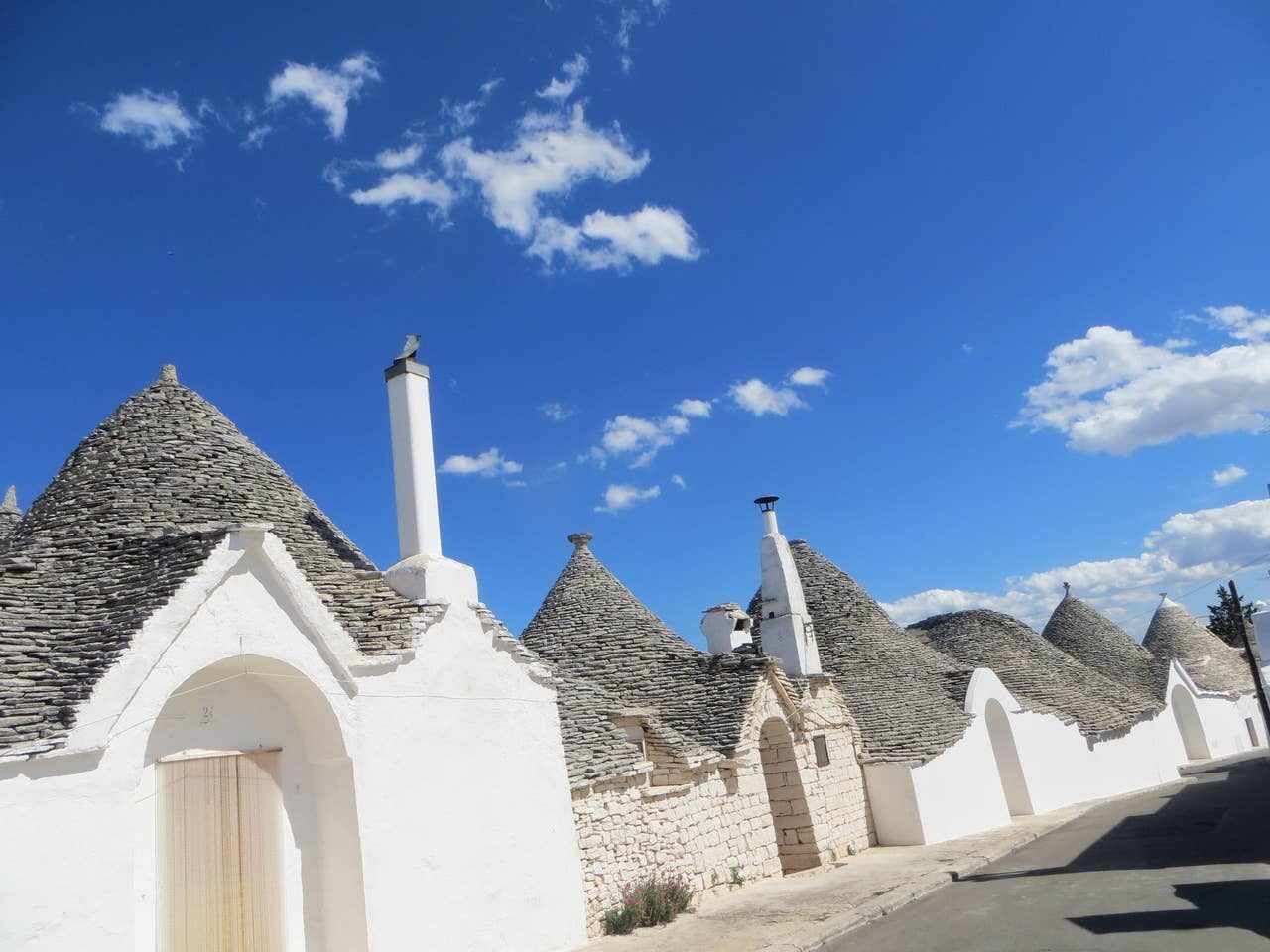 Una hilera de edificios blancos con techos cónicos, probablemente un pueblo o una ciudad tradicional.