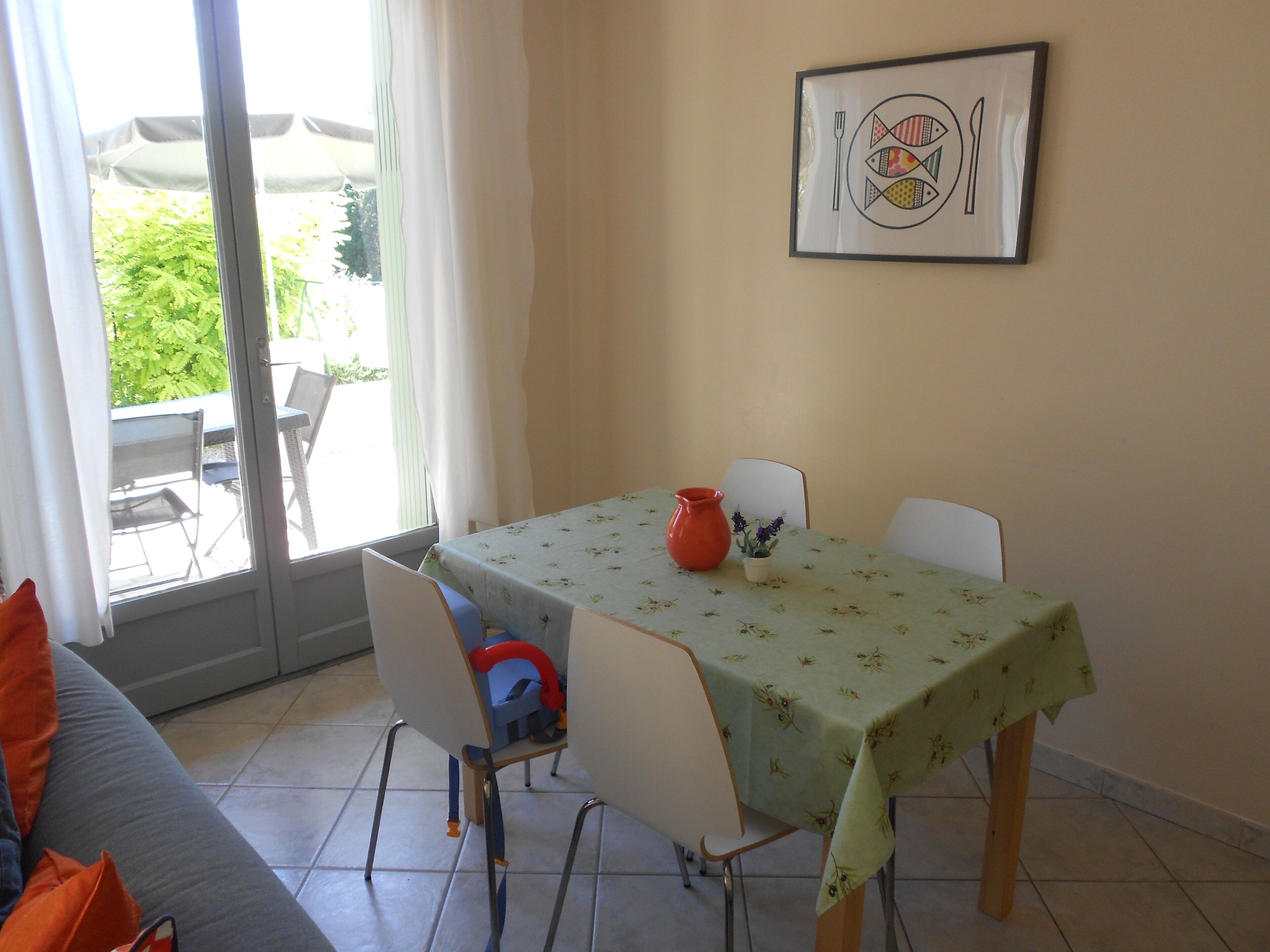 A dining area with a table, chairs, a vase, and a framed picture on the wall.