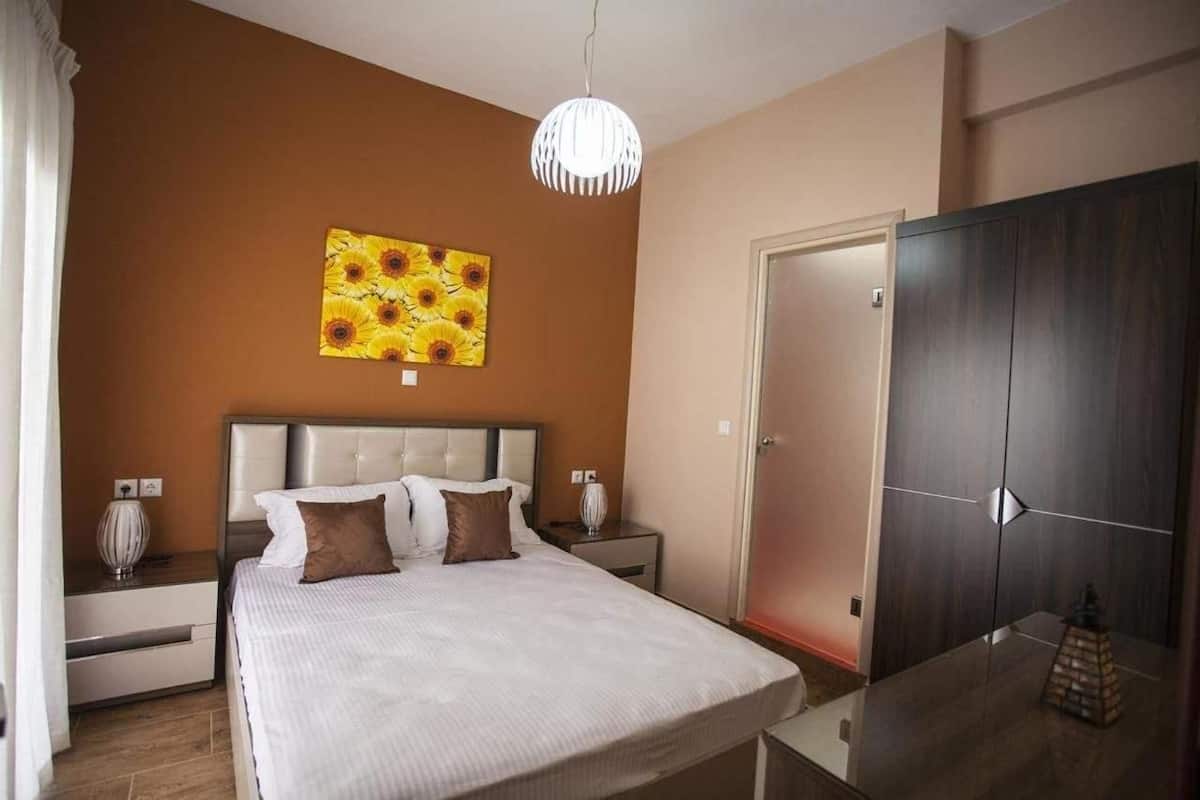 A bedroom with a bed, nightstands, a dresser, a painting, and a wardrobe.