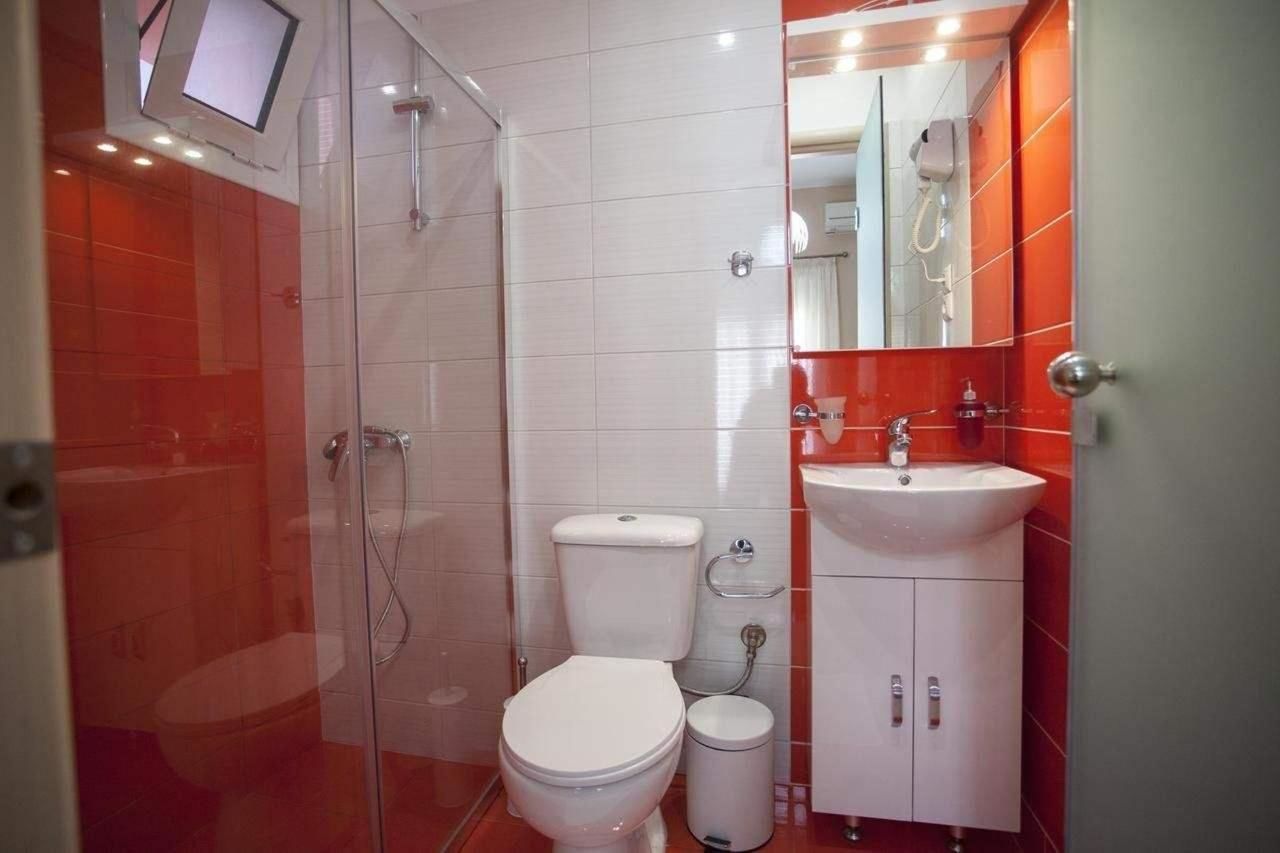 A bathroom with a glass shower enclosure, a toilet, a sink, and a mirror.