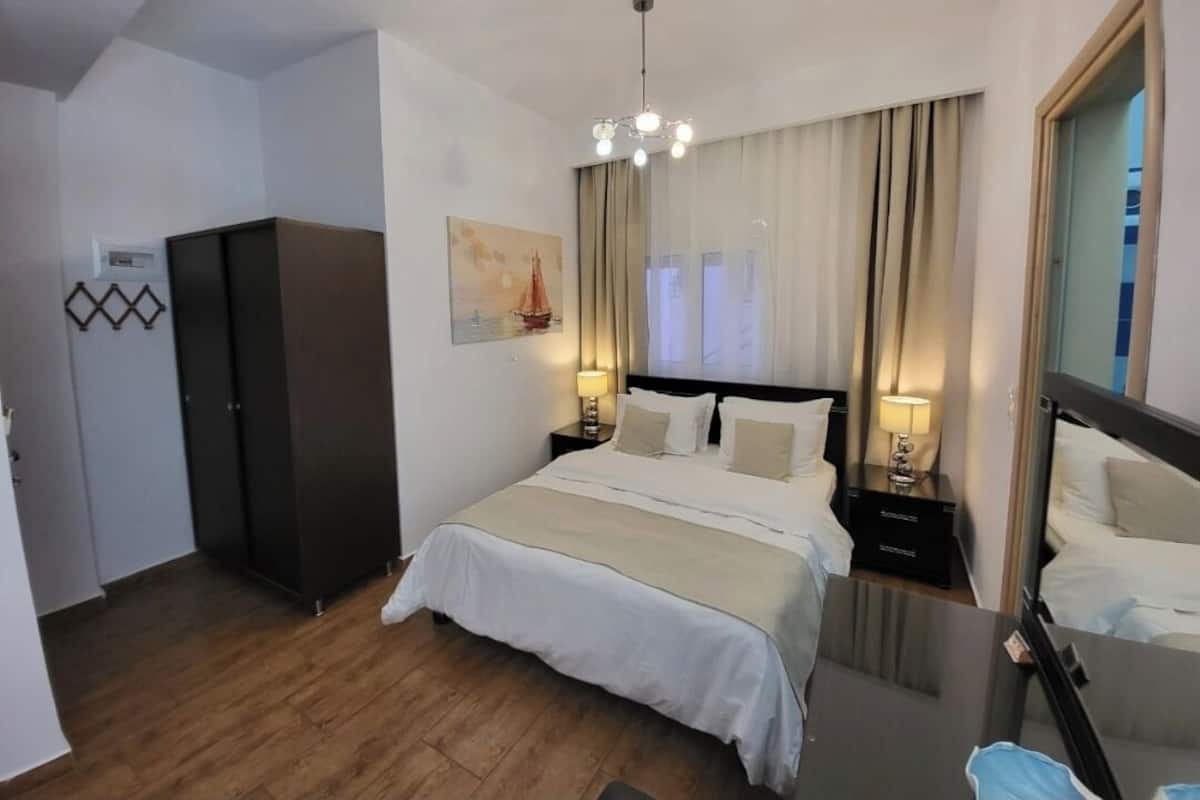 A hotel room with a bed, bedside tables, a wardrobe, and a mirror.