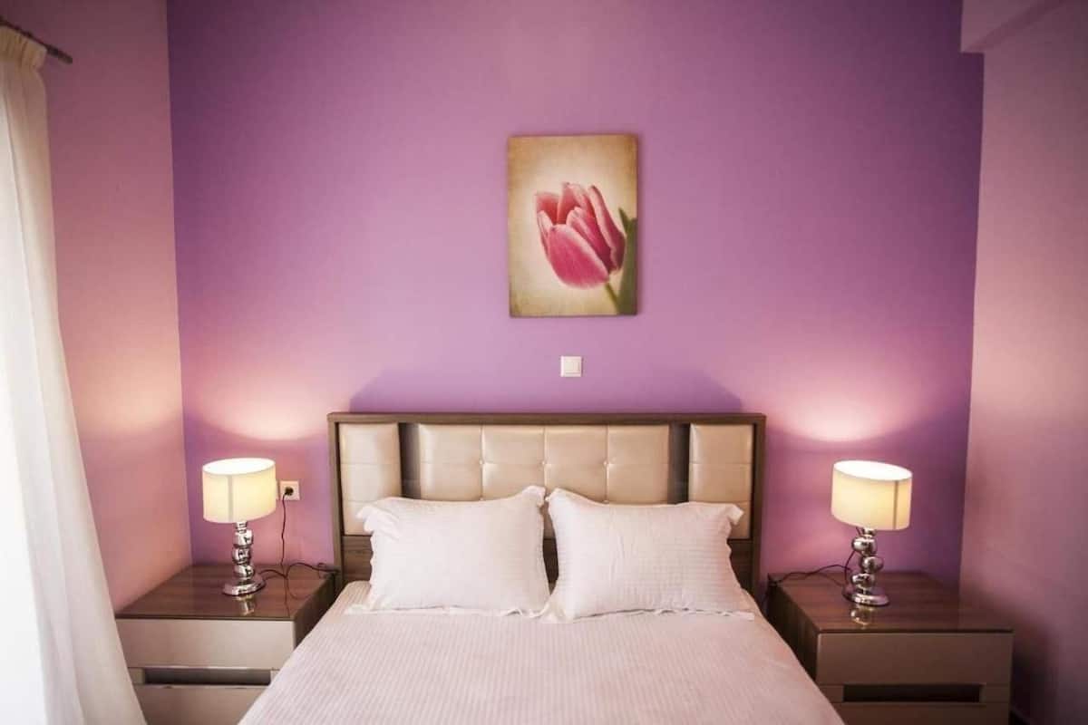 A bedroom with a bed, two nightstands, and a wall-mounted lamp.