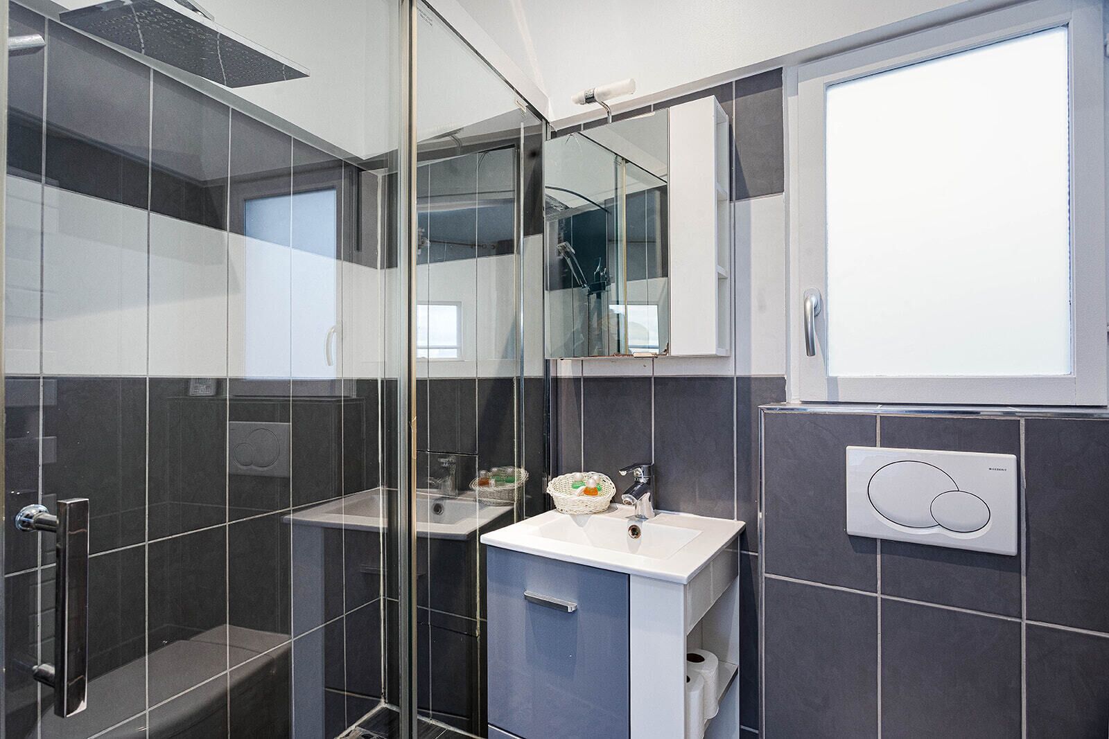 Une salle de bain moderne avec une douche à parois de verre, un lavabo avec un miroir et un porte-serviettes.