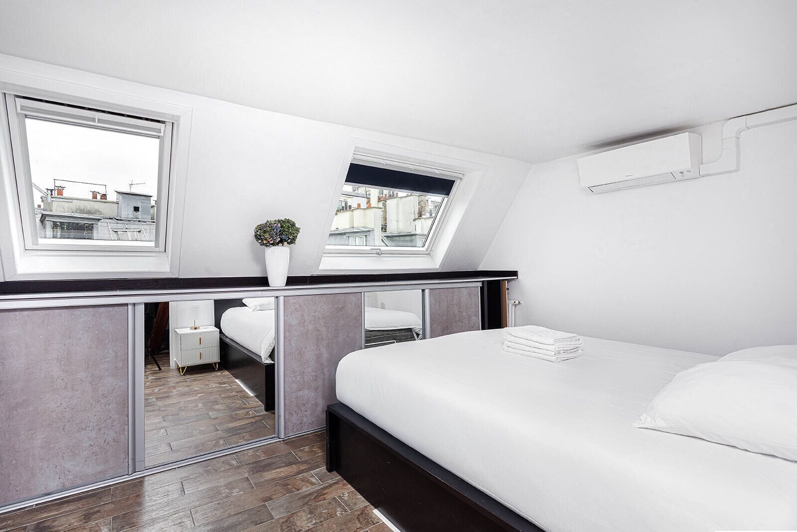 Ein modernes Schlafzimmer mit Oberlicht, einem kleinen Topfpflanzen und einem ordentlich bezogenen Bett.