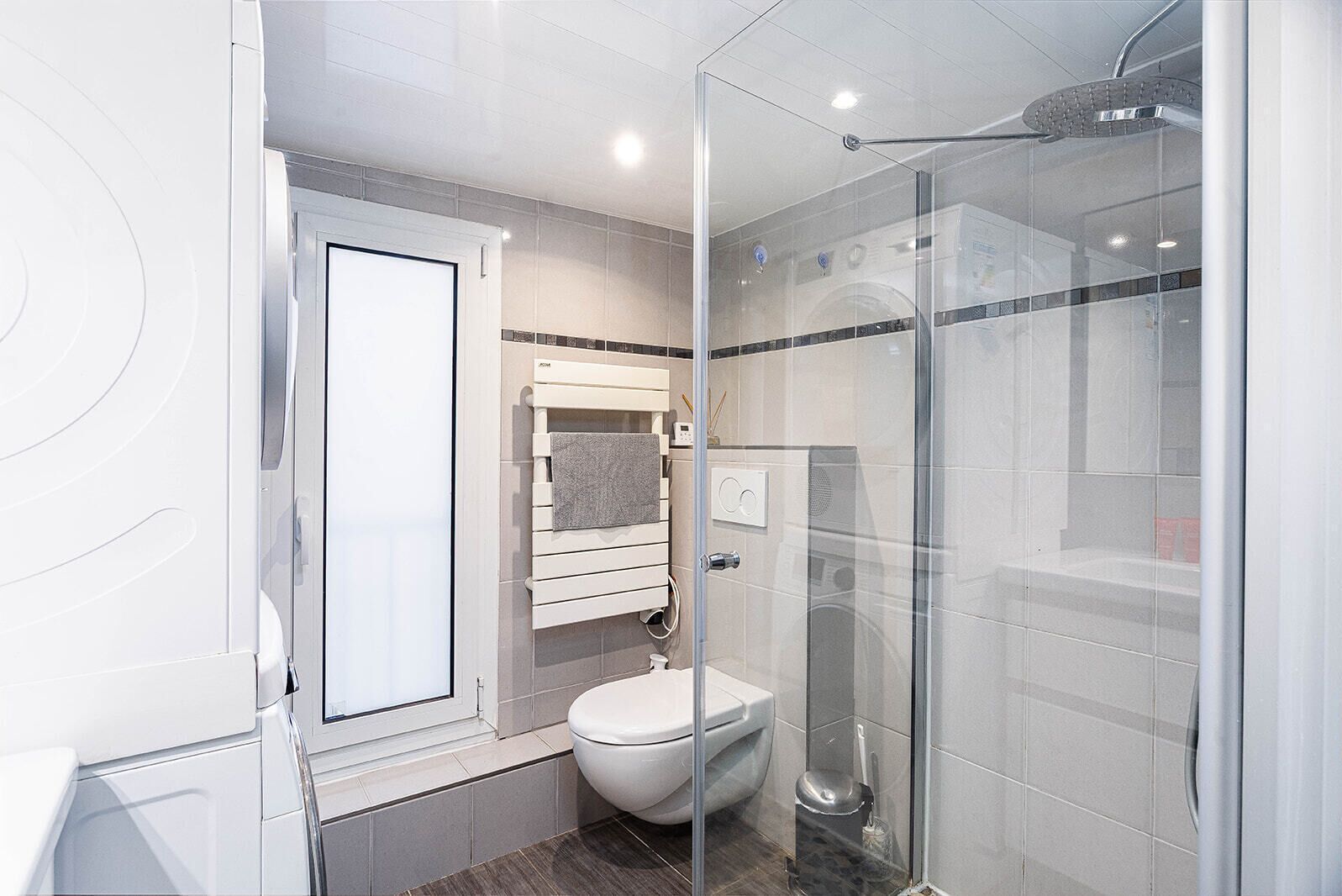 Une salle de bain moderne avec une douche à parois de verre, des toilettes et un porte-serviettes.
