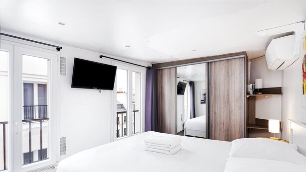 Habitació d'hotel moderna amb un llit gran, televisió de pantalla plana, un balcó i vistes a la ciutat.