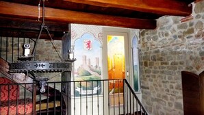 A staircase with a wrought iron railing, a decorative metal sign, and a stained glass window depicting a castle scene. - Medieval Tower Lungarno perfect location for inlove (Pratovecchio)