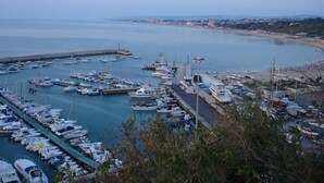 Un puerto deportivo con barcos amarrados, un muelle y una playa al fondo.