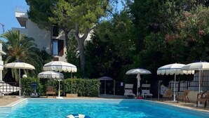 Una piscina con sillas de descanso y sombrillas.