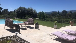 A poolside area with lounge chairs and a table, surrounded by a stone patio and a view of a mountain range. - Villa 8 people, swimming pool. Open view. Beaches 15 mins away, quiet. (Roquefort-Les-Pins)
