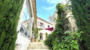 A stone staircase leading to a building with a tiled roof and a red awning. - Mas de Provence en Riviera (La Roquette-sur-Var)