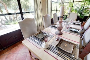 A dining table set with plates, glasses, and cutlery, surrounded by chairs. - Mas de Provence en Riviera (La Roquette-sur-Var)