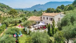 A villa with a tiled roof, surrounded by lush greenery and mountains in the background. - Mas de Provence en Riviera (La Roquette-sur-Var)