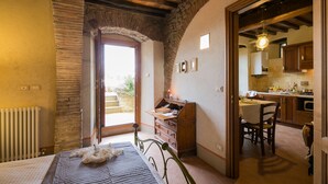 A bedroom with a bed, a wooden dresser, and a stone wall. - Romantic shelter for 2, amazing view and large equipped terrace (Cortona)