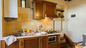 A kitchen with wooden cabinets, a microwave, and a stove. - Romantic shelter for 2, amazing view and large equipped terrace (Cortona)