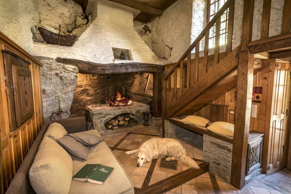 Una habitación acogedora con chimenea de piedra, vigas de madera, un sofá y un perro.